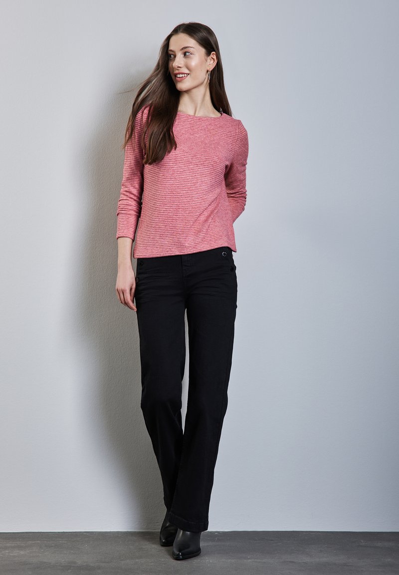 Haut à manches longues à rayures rouges et blanches associé à un pantalon droit noir et des bottes à talons noires. Texture lisse avec une coupe décontractée.