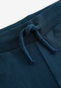 Marineblauwe joggingbroek met een gestructureerde ribgebreide tailleband, voorzien van een geknoopt trekkoord en een gladde stof.