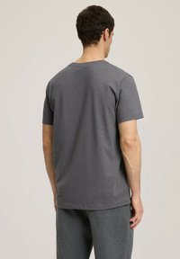 Szara bawełniana koszulka, krótki rękaw, okrągły dekolt, luźny krój, gładki design, brak widocznych wzorów lub elementów metalowych.