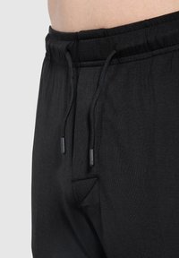 Schwarze Sportshorts mit einem elastischen Bund, verstellbarem Kordelzug und Seitentaschen. Weicher Stoff und lockere Passform.
