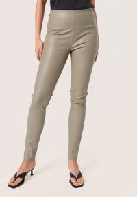 High-waisted, fitted trousers in a soft olive green faux leather. Smooth texture with a sleek design and no visible seams.
