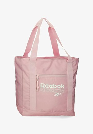 Grande borsa a spalla rosa chiaro con due manici, tasca frontale con cerniera e logo Reebok bianco sulla tasca.