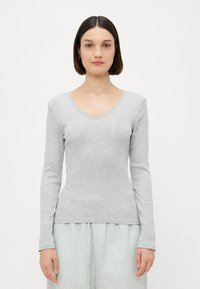 Haut à manches longues gris en texture côtelée avec un décolleté en V. Associé à un bas rayé, il présente une silhouette ajustée et un tissu doux.