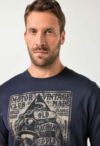 Tmavě modré bavlněné tričko s vintage grafickým potiskem s tématem motorek a ošoupaným nápisem na přední straně.