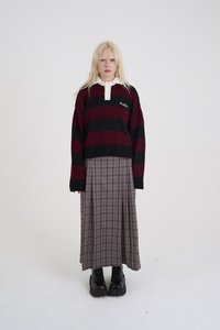 Vyno raudonos ir juodos spalvų dryžuotas megztinis su smėlio spalvos apykakle, derinamas su ilgu pilko languoto audinio sijonu ir juodais stambiais auliniais batais su raišteliais.