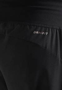 Shorts de sport noirs Dri-FIT avec une texture lisse, une taille élastique et un logo simple affiché en évidence à l'arrière.