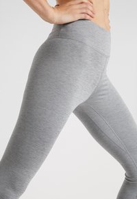 Leggings atletici grigi realizzati in un tessuto testurizzato. Hanno una vita alta e un design aderente con cuciture sottili per un tocco di dettaglio.