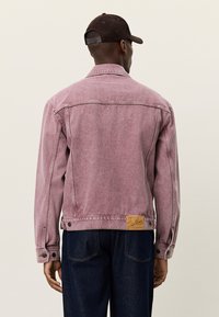 Ροζ τζιν μπουφάν με μακριά μανίκια, μανσέτες με κουμπιά και υφασμένη ετικέτα στο πίσω στρίφωμα. Το μπουφάν έχει ίσια γραμμή και ραφές για διακόσμηση.