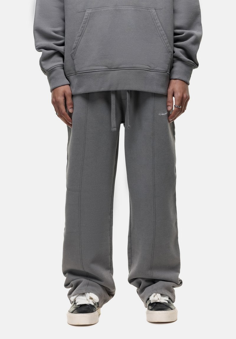 Grijze sweatshirt met een kangoeroezak en losvallende grijze joggingbroek. Beide hebben een zachte textuur en zichtbare stiksels.