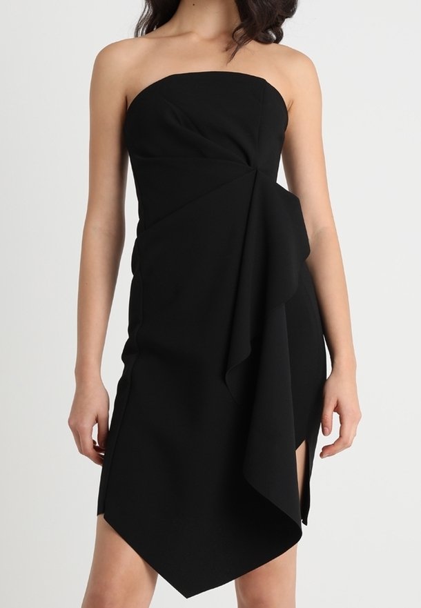 Černé šaty bez ramínek s přiléhavým živůtkem, římským postranním detailem a asymetrickým lemem. Vyrobeno z hladké tkaniny s matným povrchem.