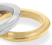 Zwei glatte Metallringe sind abgebildet, einer silberfarben und einer goldfarben. Beide haben eine ovale Form mit einer polierten Oberfläche und einem eingravierten "Calvin Klein"-Logo.