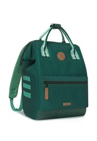 Groene canvas rugzak met gestreepte handvaten, een ritsvak aan de voorkant en een bruine leren logo patch. Voorzien van gepolsterde schouderbanden en een gestructureerde bodem.