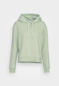 Sweatshirt à capuche vert clair avec un design court, des manches longues et des cordons de serrage. Il présente un petit logo en forme de cœur sur la poitrine. Fabriqué en tissu doux.