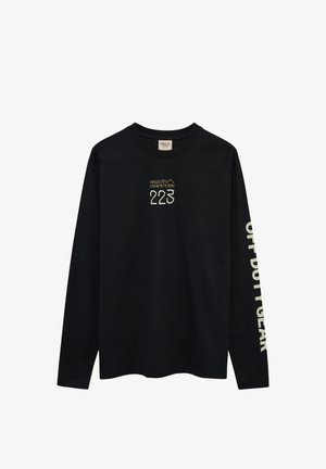 Schwarzes Langarmshirt mit Rundhalsausschnitt, auf der Brust die Zahl "223" und kleiner Text, sowie weißer Text entlang eines Ärmels.