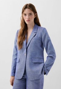 Lichtblauwe blazer van textuurstof met twee voorkruisen, eensluiting met één knoop en een notch-kraag. Fijne stippen door het hele jack.