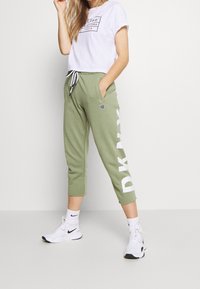 Gröna avslappnade sweatpants med vit "DKNY" tryck, dragsko i midjan, sidofickor, ihopparade med en vit grafisk t-shirt och vita sneakers.
