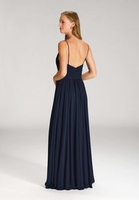 Ein marineblaues Abendkleid mit dünnen Trägern, einem leicht gerafften Oberteil und einem fließenden, bodenlangen Rock. Glattes Material mit weicher Textur.