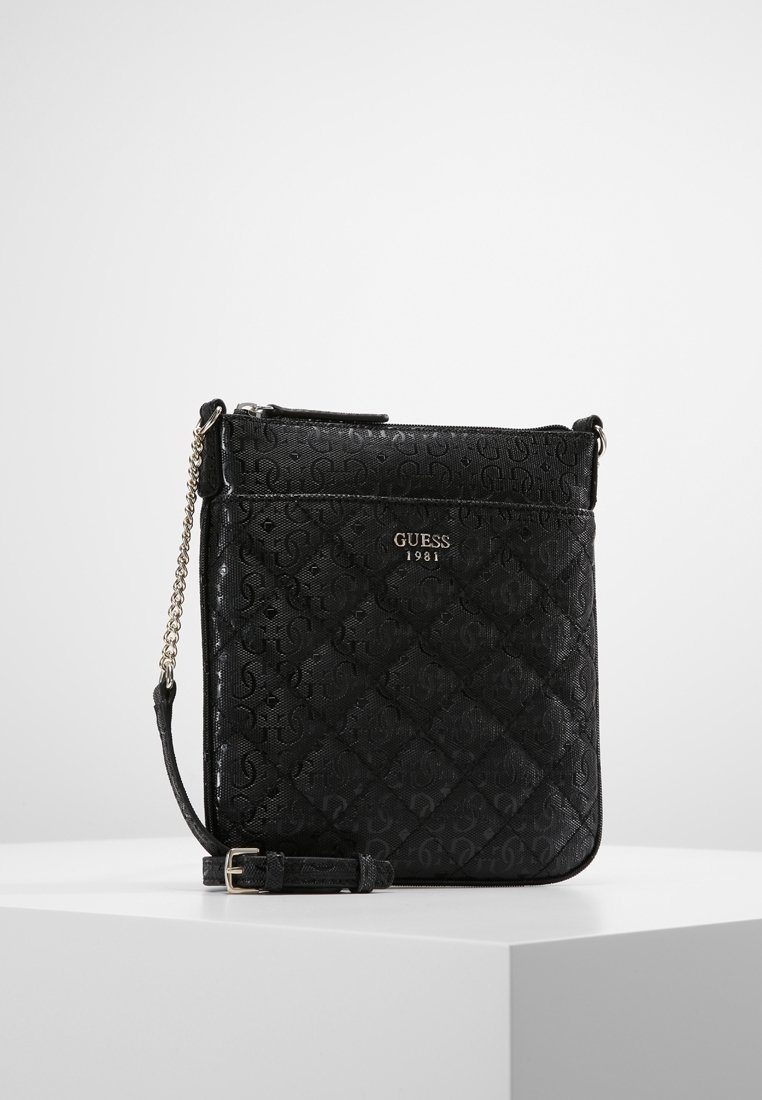 Černá prošívaná crossbody taška s embosovaným vzorem loga, zapínáním na zip a popruhem s řetízkem. Hladká textura a kompaktní obdélníkový tvar.