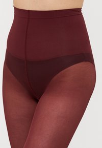 Collant bordeaux a vita alta con una parte inferiore liscia e trasparente e una parte superiore testurizzata, dotati di un ampio elastico in vita per il massimo comfort.