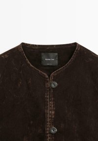Brun fløjlsjakke med rund hals, to knapper foran og glat tekstur. Label indeni med teksten "Massimo Dutti."