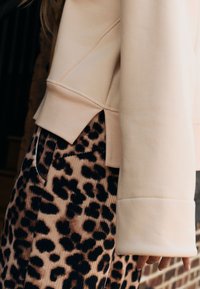 Lichtbeige sweatshirt met geribde boord, gecombineerd met een corduroy rok met luipaardprint in tinten bruin en zwart; voorzien van zijsplitsingen.