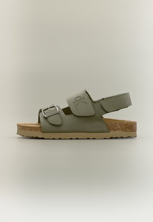 Oliwkowo zielony sandał z otwartym palcem, regulowaną klamrą i paskami na rzepy, korkową wkładką i teksturowaną gumową podeszwą, widok z boku.