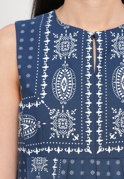 Kankaamaton mekko tummansinisen kankaan, jossa on valkoisia kukka- ja geometrisia kuvioita, pyöreä pääntie ja edessä avainaukko-yksityiskohta.