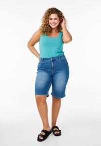 Hele sinine tops, teksast Bermuda lühikesed püksid ja mustad sussid, millel on lipsu dekoratsioonid. Igapäevane riietus, millel on mugav lõige ja sile tekstuur.