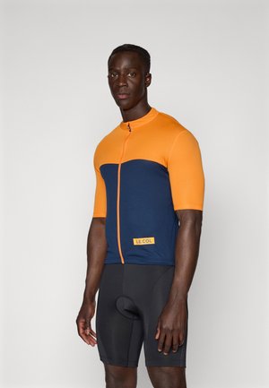 Maillot de cyclisme à manches courtes en orange et bleu marine, doté d'une fermeture éclair à l'avant, d'un design ajusté et du logo "LE COL" sur le bas à l'avant.