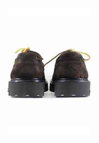 Scarpe in suede marrone con punta rotonda, suola nera piatta e lacci gialli; presentano una finitura texture e un design minimalista.