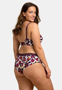 Ensemble de soutien-gorge et culotte multicolore avec des motifs floraux en violet, rose et jaune sur fond blanc, avec une dentelle sur la taille.
