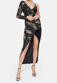 Black dress featuring one long sequin sleeve and a deep V-neck, with a side slit and floral gold accents, smooth fabric texture.
