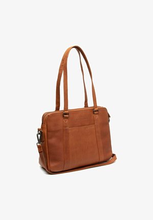 Brown leather bag with two long handles, a zip closure, front pocket, and adjustable strap. Smooth texture and rectangular shape.