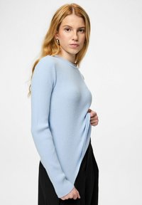 Gaiši zils ribots garām piedurknēm džemperis ar apaļu kakla izgriezumu un sānu spraugu. Mīksta tekstūra un pieguloša piegriezuma, kombinēts ar melnām augsta jostasvietas biksēm.