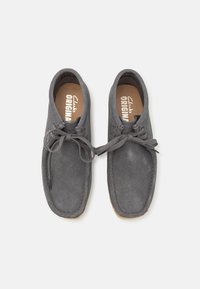 Scarpe in suede grigio con punta rotonda, caratterizzate da una laccatura bicolore e dettagli cuciti. L'interno presenta una soletta con logo.