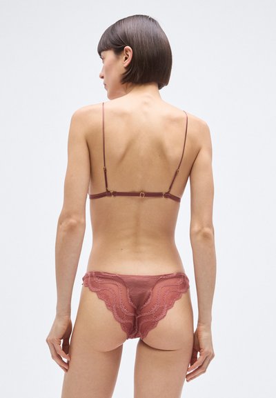 Set perila rožnate barve z nežnim čipkastim robom. Nastavljivi tanki naramnice in valoviti robovi. Mehki, prosojni material z gladko teksturo.