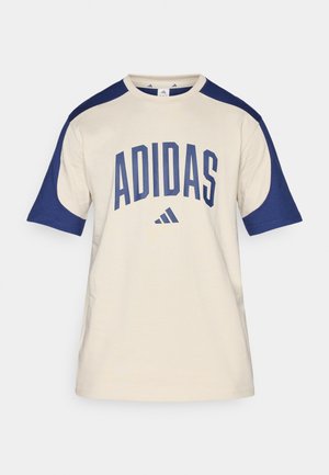 Kremowy t-shirt z krótkim rękawem z granatowymi rękawami raglan. Na przodzie wyraźne logo "ADIDAS" w kolorze granatowym oraz mały trójkątny logotyp poniżej. Wykonany z miękkiej bawełny.