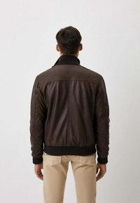 Bruine leren bomberjack met een geribde kraag en manchetten, met een gladde textuur en gestikte details op de rug.