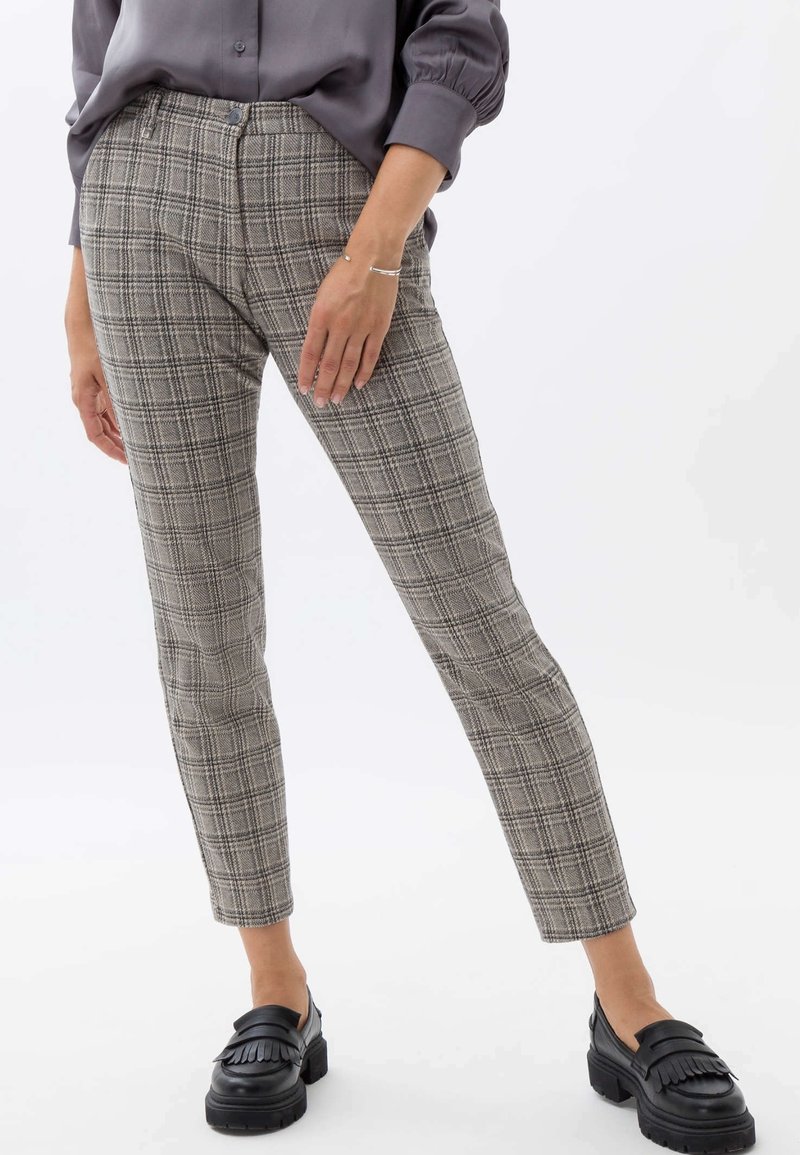 Pantaloni grigi a quadri con un design aderente, caratterizzati da una vita alta, tasche e una texture liscia. Abbinati a mocassini neri.