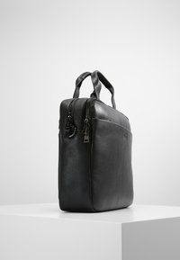 Svart läder laptopväska med dubbel dragkedjestängning, två handtag, slät yta, rektangulär form och en minimalistisk design.