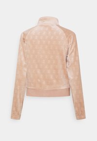 Velvet zip-up jacka i mjuk rosa med ett upprepat logomönster, med hög krage och ribbade muddarna vid ärmarna och nederkanten.