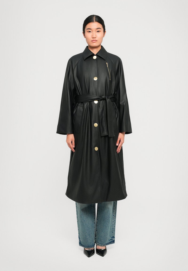 Cappotto trench in finta pelle nera con grandi bottoni dorati, vita con cintura e tasca con zip. Caratterizzato da maniche ampie e design lungo fino al ginocchio.