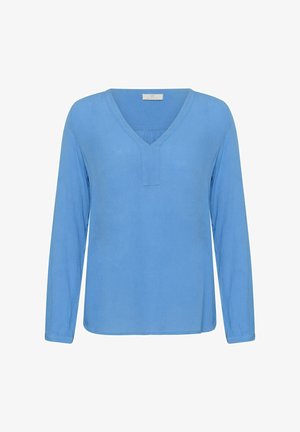 Svetlo modra bluza z dolgimi rokavi in V-izrezom ter subtilno teksturo. Rob je raven, kroj sproščen, detajli šivov so minimalni.