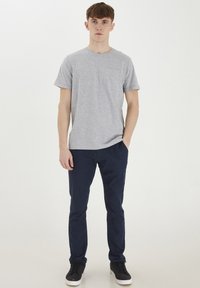 T-shirt in cotone grigio con maniche corte e taschino sul petto, abbinato a pantaloni blu navy, con vestibilità slim. Include sneakers nere.