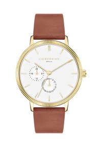 Gouden horloge met een witte wijzerplaat, minimalistische uurmarkeringen en een subdial. Voorzien van een bruine lederen band en een gestructureerde lunette.