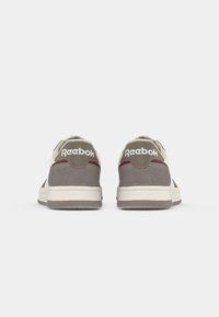Adidași Reebok cu un superior din suede gri, cu accente crem, un logo alb, guler căptușit și o talpă groasă din cauciuc.