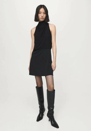 Svart ärmlös klänning med hög halsringning, slät textur, kombinerad med knähöga svarta stövlar med spetsig tå.