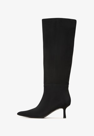 Bota negra hasta la rodilla en suave ante con puntera afilada y un delgado tacón de aguja. Presenta un diseño limpio y mínimos acentos de hardware.