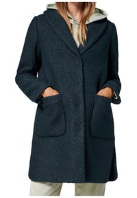 Tumma teksturoitu päällystakki, jossa on käännetty kaulus, kaksi etutaskua ja rento istuvuus. Päällä vaaleanharmaa huppari.