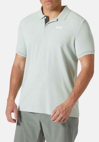 Polo de color verde claro en una tela suave, con un cuello negro y un logo blanco en el pecho. Mangas cortas y un diseño de ajuste relajado.